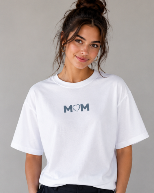Woman wearing a white t-shirt with 'MOM' printed on it against a gray background
